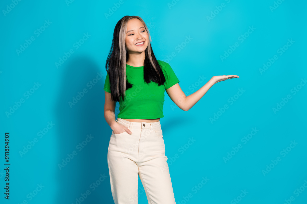 Wall mural Photo of nice young girl hand hold empty space wear green t-shirt isolated on teal color background