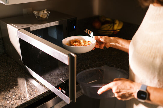 woman standing in kitchen in her home eating lunch