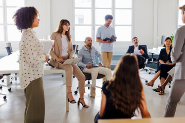 Diverse team of professionals listening to manager during meeting