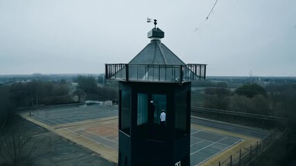 Guard Tower Overlooking Prison Basketball Courts on a Cloudy Day Generative AI - Powered by Adobe