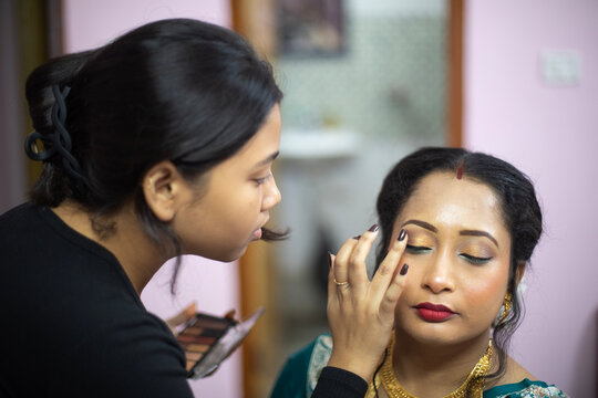 Indian woman taking makeup before attending a marriage programme