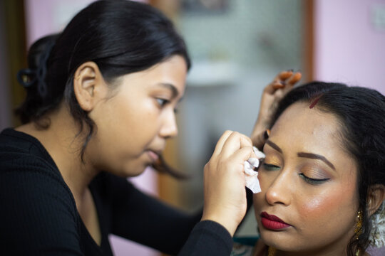 Indian woman taking makeup before attending a marriage programme