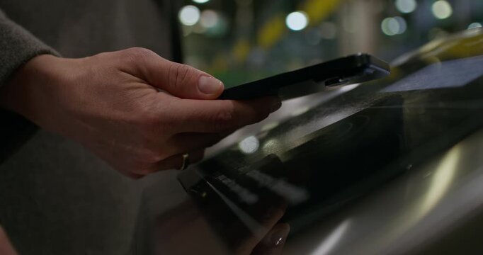 A woman puts her mobile phone to the terminal in the subway and passes through the turnstile. Close-up of her hand, an unrecognizable person