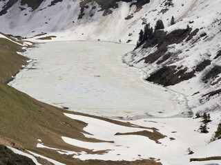Lac of Lessy in spring in Haute Savoie : the ice is melting at the edge of the alpine lake in may....