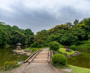 Walkway leading to small island in the middle of a well manicured Japanese garden