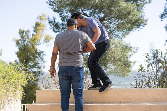 Father Assists Son Up Steps Against Nature Backdrop