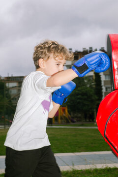 A boxing coach gives a boy a workout in the park