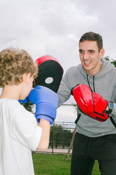 A boxing coach gives a boy a workout in the park