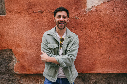 Smiling man with jacket against rustic red wall