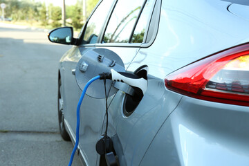 Naklejka premium Charging modern electric car from station outdoors