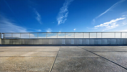 Obraz premium 晴れた校舎の屋上。コンクリート、手すり、青空のある屋上の風景。A sunny day on the roof of a school building. A rooftop view with concrete, railings and blue sky.