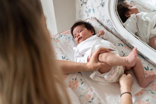 Mother changing her newborn baby girl's diaper on a changing table