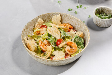 Fresh Shrimp Caesar Salad with Toasted Bread and Cherry Tomatoes in Ceramic Bowl