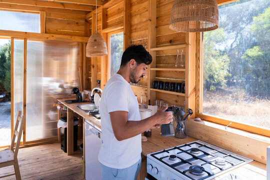 Man preparing coffee in sustainable tiny house kitchen