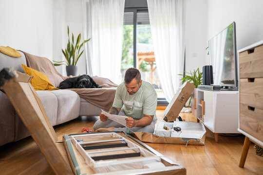 Focused man reading instructions assembling furniture