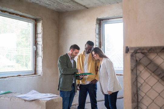 Broker Showing Construction Plans To Multiracial Couple