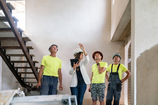 Female Architect Explaining Construction Plan To Builders