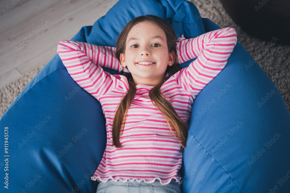 Sticker Photo portrait of cute small schoolgirl lying bean bag relaxed hands behind head home education school interior