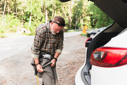 Fisherman changing clothing by Car for a Day at the Lake