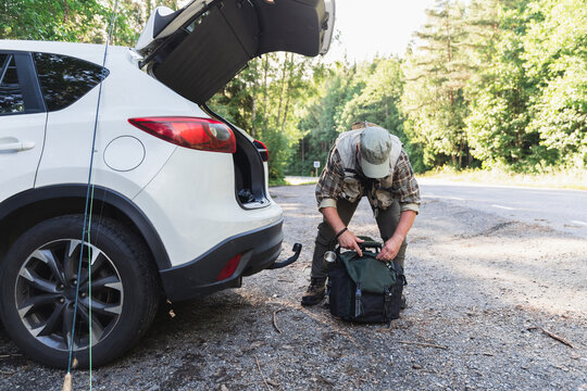 Fisherman Preparing Fishing Rod by Car for a Day at the Lake