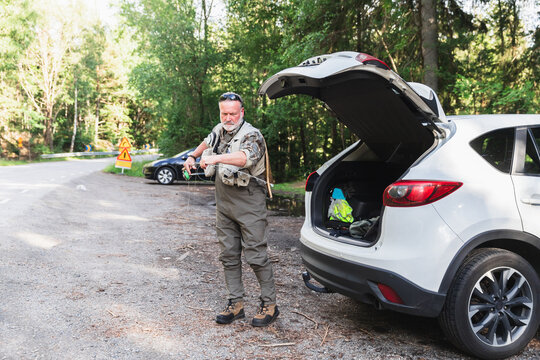 Fisherman Preparing Fishing Rod by Car for a Day at the Lake