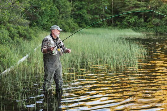 Fisherman Standing in Lake Amidst Scenic Wilderness