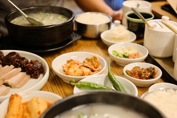 Man eating dinner of soondae gukbap (blood sausage soup), served in an earthenware pot, with steamed rice and assorted banchan, such as kimchi, at Yeodongsik - a Korean restaurant in Sydney, Australia