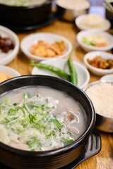 A clay pot of soondae gukbap (blood sausage soup) with steamed rice and assorted banchan, such as...