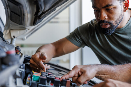 Closeup of mechanic explaining coworker while repairing car at garage