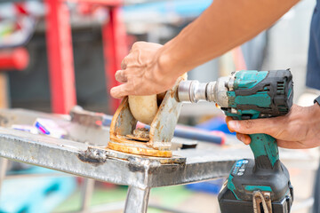 Close up technician hand use cordless block tighten trolley wheel nut.