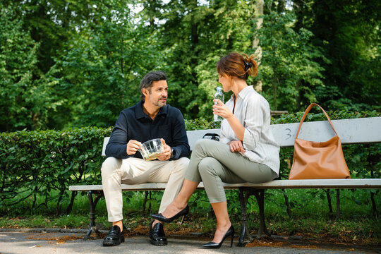 Man and woman eating lunch outdoors - Powered by Adobe