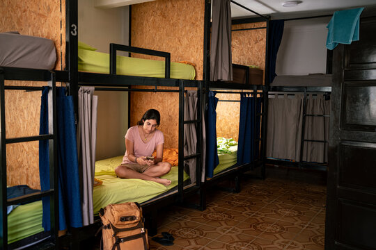 backpacker woman in her hostel room using her phone