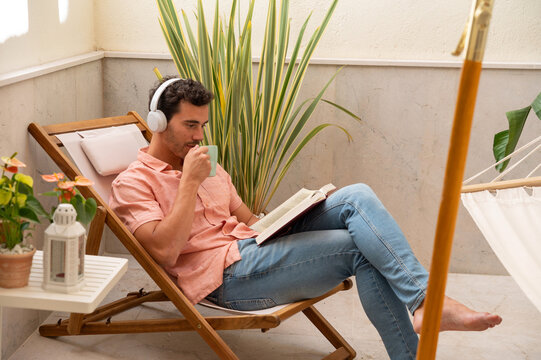 Relaxing man listening to music, reading a book and drinking coffee