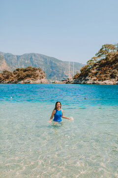 Tanned happy woman at summer beach, walking forward in warm sea water 