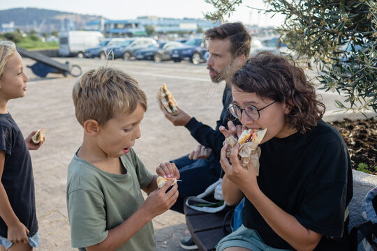 Spouses and children eating street food outdoors