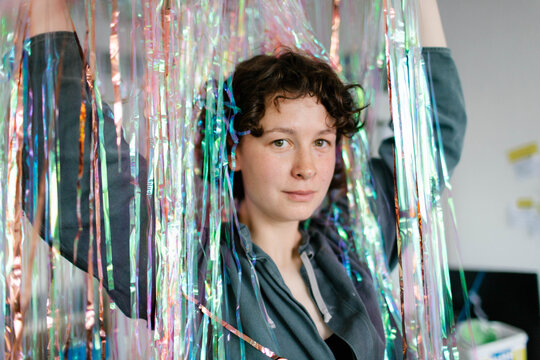 a young woman  holds a shiny tinsel above her head