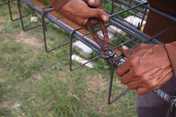 Construction workers use wire to tie structural steel without wearing gloves