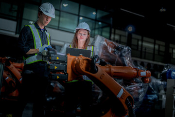 team engineers inspecting on machine with smart tablet. Worker works at heavy machine robot arm. The welding machine with a remote system in an industrial factory. Artificial intelligence concept.