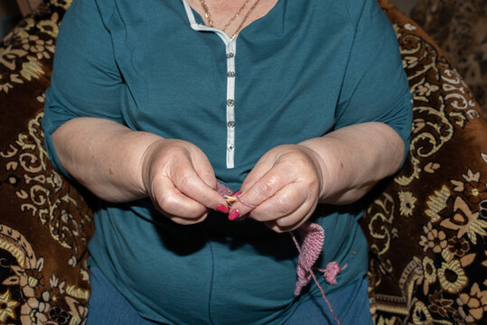 Close-Up Of Elderly Woman's Hands Knitting Pink Yarn