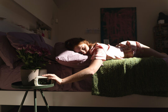 Woman Reaching for Alarm Clock in Bed