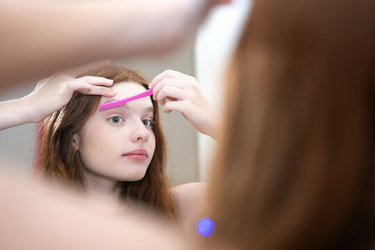 Woman Shaping Eyebrows with Razor
