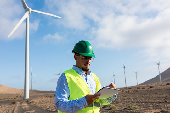 Worker at a wind power plant performs a routine check on some turbines