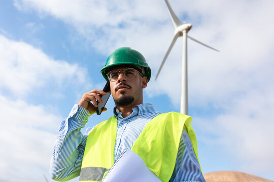 Member of the staff at a windmill farm uses his phone to make a call