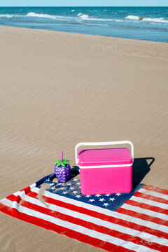 bootle, cooler and american flag on a lonely beach