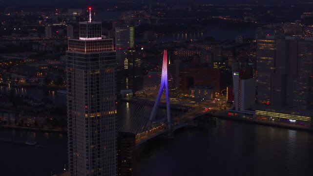 Lvely city lights and bustling nightlife of Rotterdam from above, showcasing the illuminated erasmus bridge and surrounding skyscrapers at night