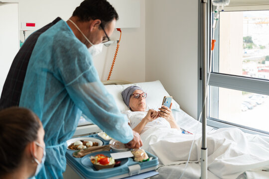 Nurse bringing meal tray to female patient