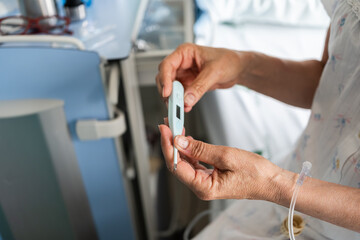 patient checking temperature with digital thermometer