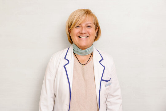 Smiling senior doctor in white coat with scarf looking at camera