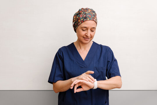 Healthcare professional in blue scrubs checking a smartwatch