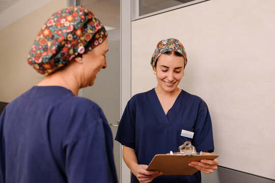 Healthcare professionals in scrubs reviewing case notes with clipboard